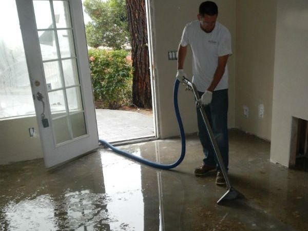 Technician extracting standing water from a flooded interior floor